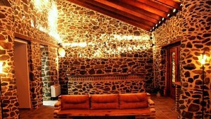 A stone-walled interior with a wooden bench and a table with fruit. - Loggas Hotel (Kastoria)
