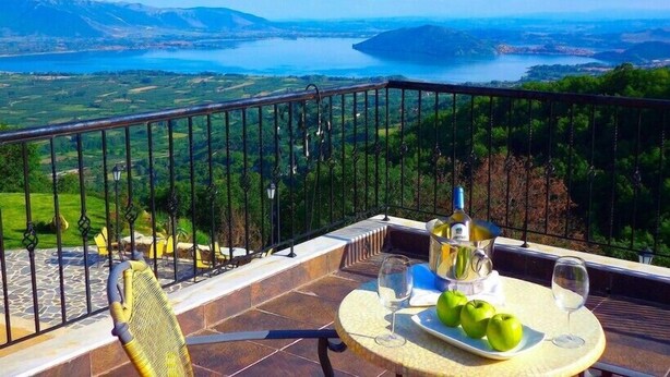 A balcony with a table set for two, a bottle of wine, and a plate of apples. - Loggas Hotel (Kastoria)