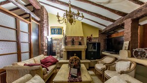 A cozy living room with a fireplace, comfortable seating, and a television. - La Casona Albaida (Albaida)
