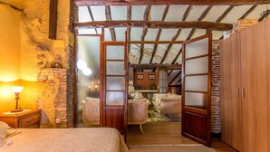 A rustic bedroom with a wooden ceiling, a bed with a headboard, a nightstand, and a lamp. - La Casona Albaida (Albaida)
