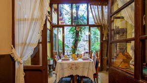 A dining area with a table set for four, a potted plant, and a view of greenery outside. - La Casona Albaida (Albaida)