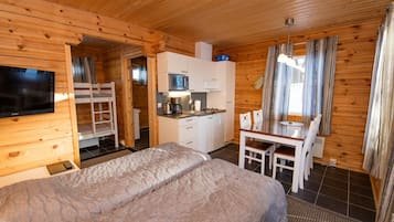 A wooden cabin with a bunk bed, kitchenette, and a dining area.