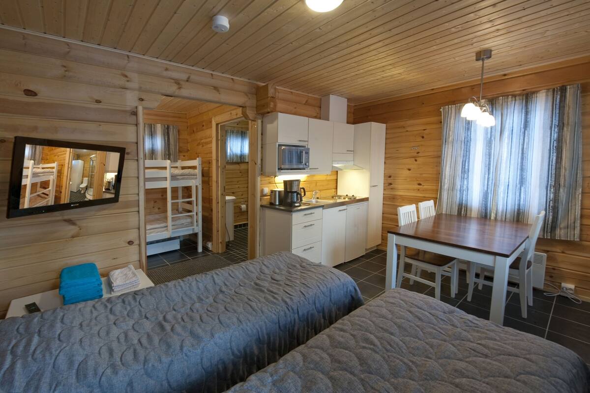 Ein gemütliches Blockhauszimmer mit zwei Betten, einer Küchenzeile und einem Essbereich.