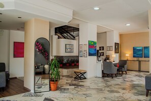A spacious lobby with a marble floor, seating area, staircase, and artwork on the walls. - Z Otel (Cesme)