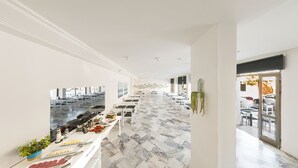 A spacious corridor with a marble floor, white walls, and a long dining table with chairs. - Z Otel (Cesme)