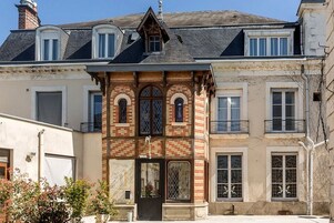 A two-story building with a brick facade, arched windows, and a balcony.