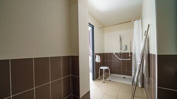 A modern bathroom with a shower, a toilet, and a handrail.