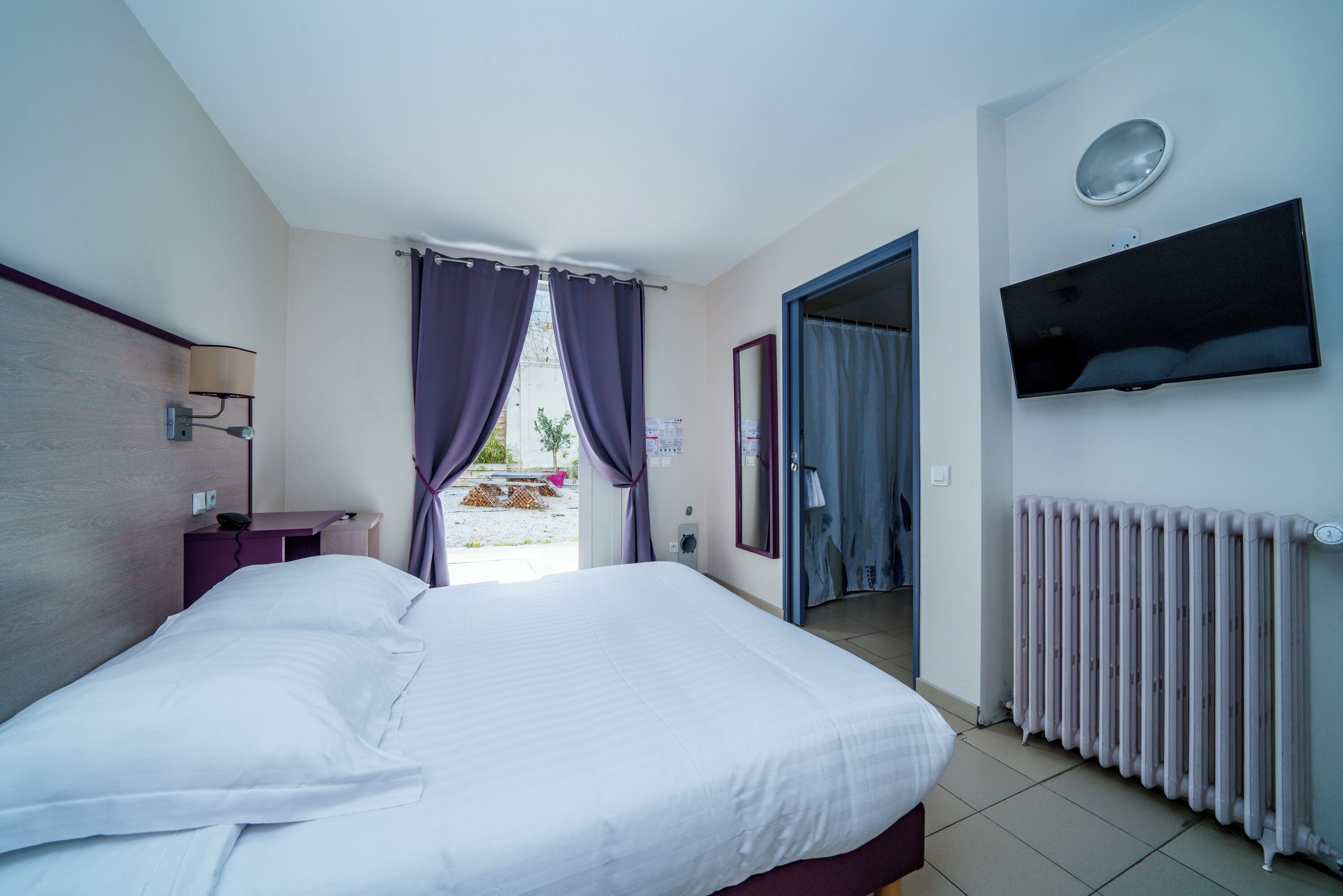 Habitación de hotel con cama, escritorio, televisor y vista al exterior.