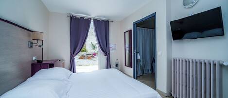Habitación de hotel con cama, escritorio, televisor y vista al exterior.
