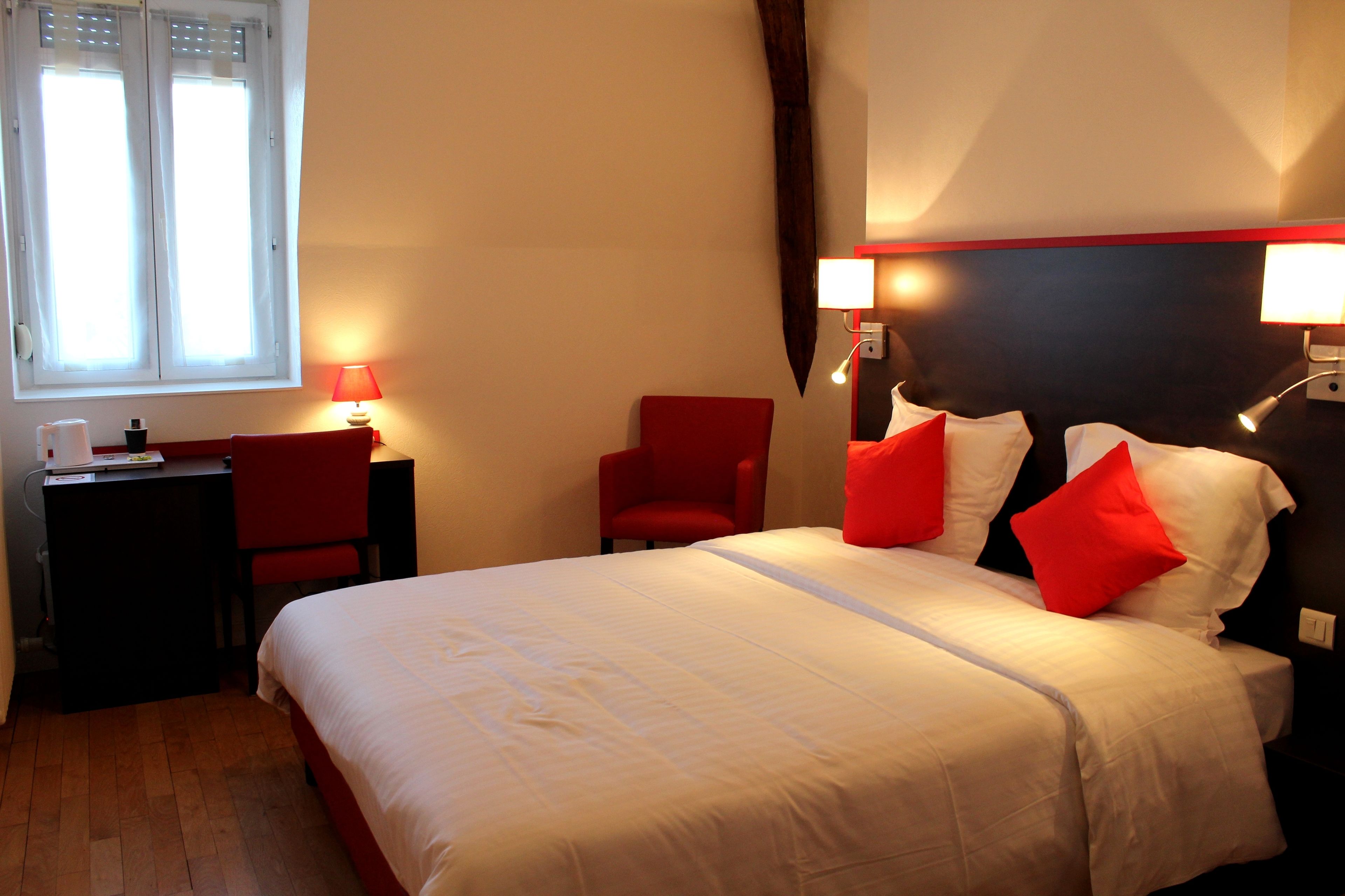 A hotel room with a bed, a desk, a chair, and two bedside lamps.