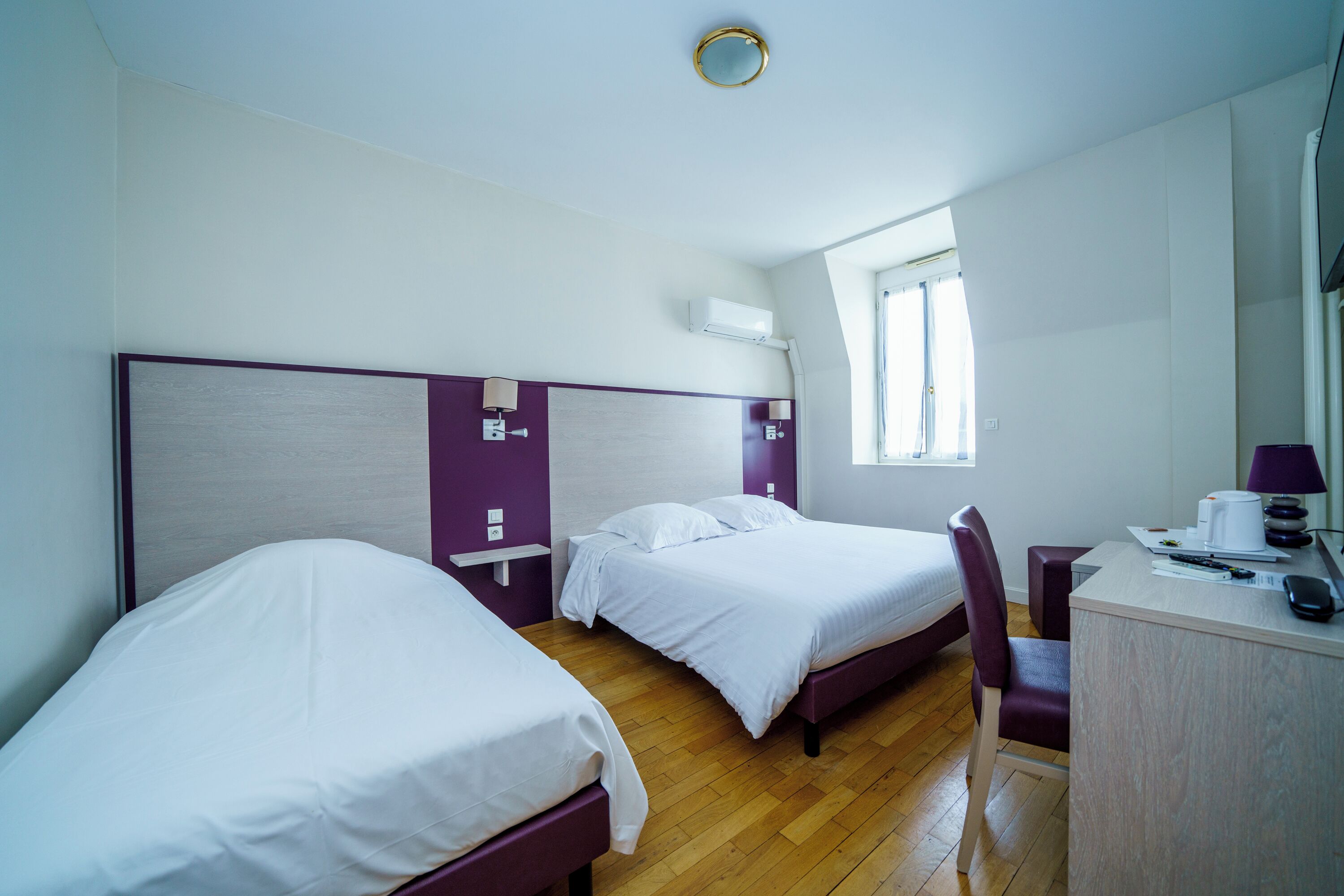 Una camera d'albergo con due letti, una scrivania e una sedia.