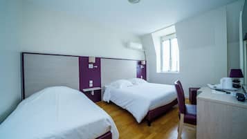 Una camera d'albergo con due letti, una scrivania e una sedia.
