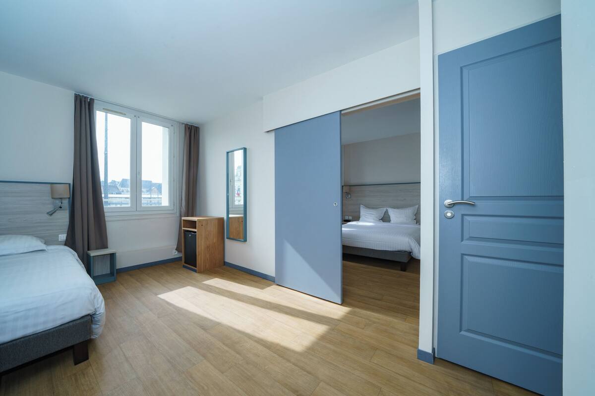 Ein Hotelzimmer mit Bett, Schreibtisch, Spiegel und Kleiderschrank.