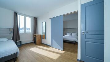 Une chambre d’hôtel avec un lit, un bureau, un miroir et une armoire.