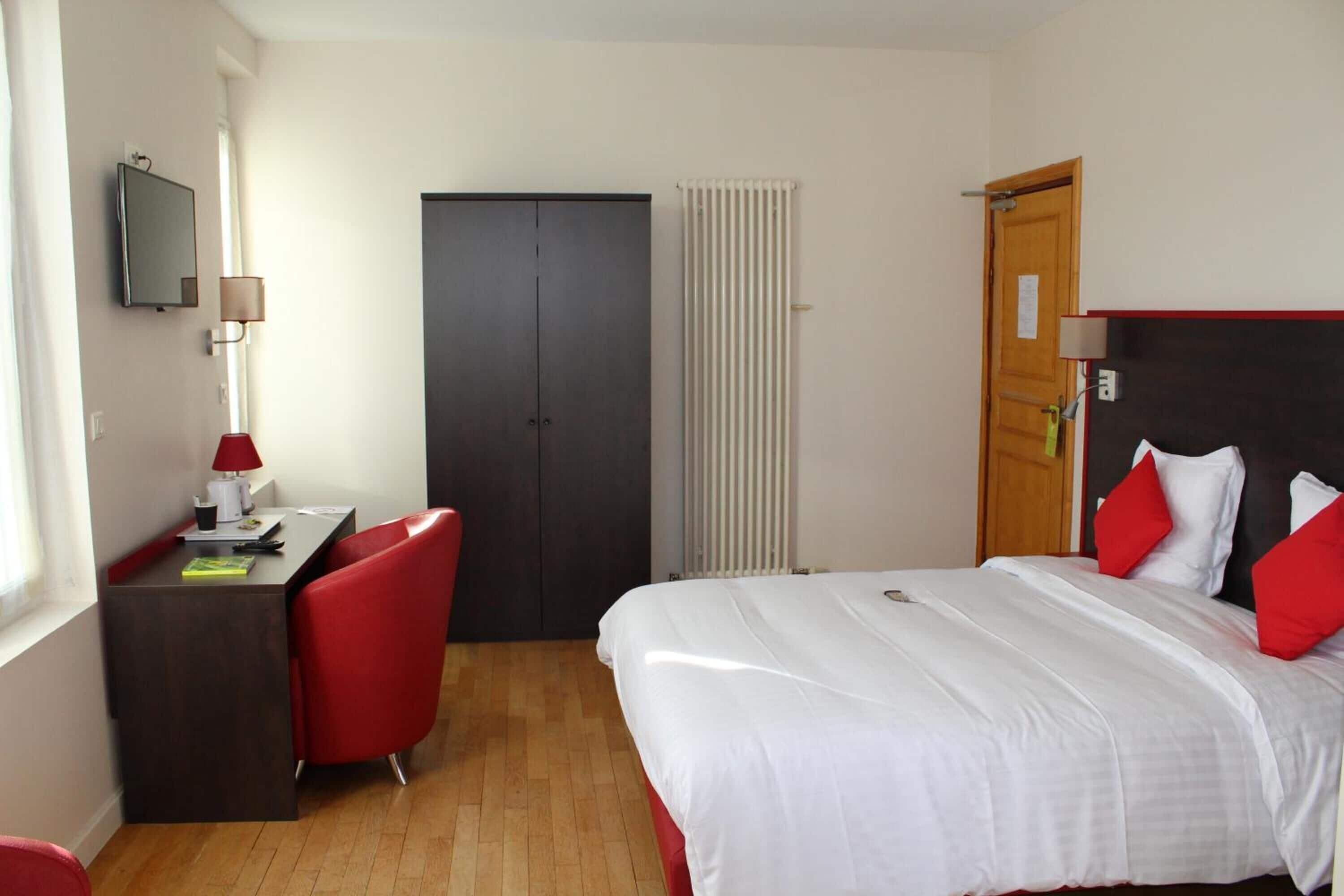 Een hotelkamer met een bed, een bureau, een stoel, een kledingkast en een radiator.