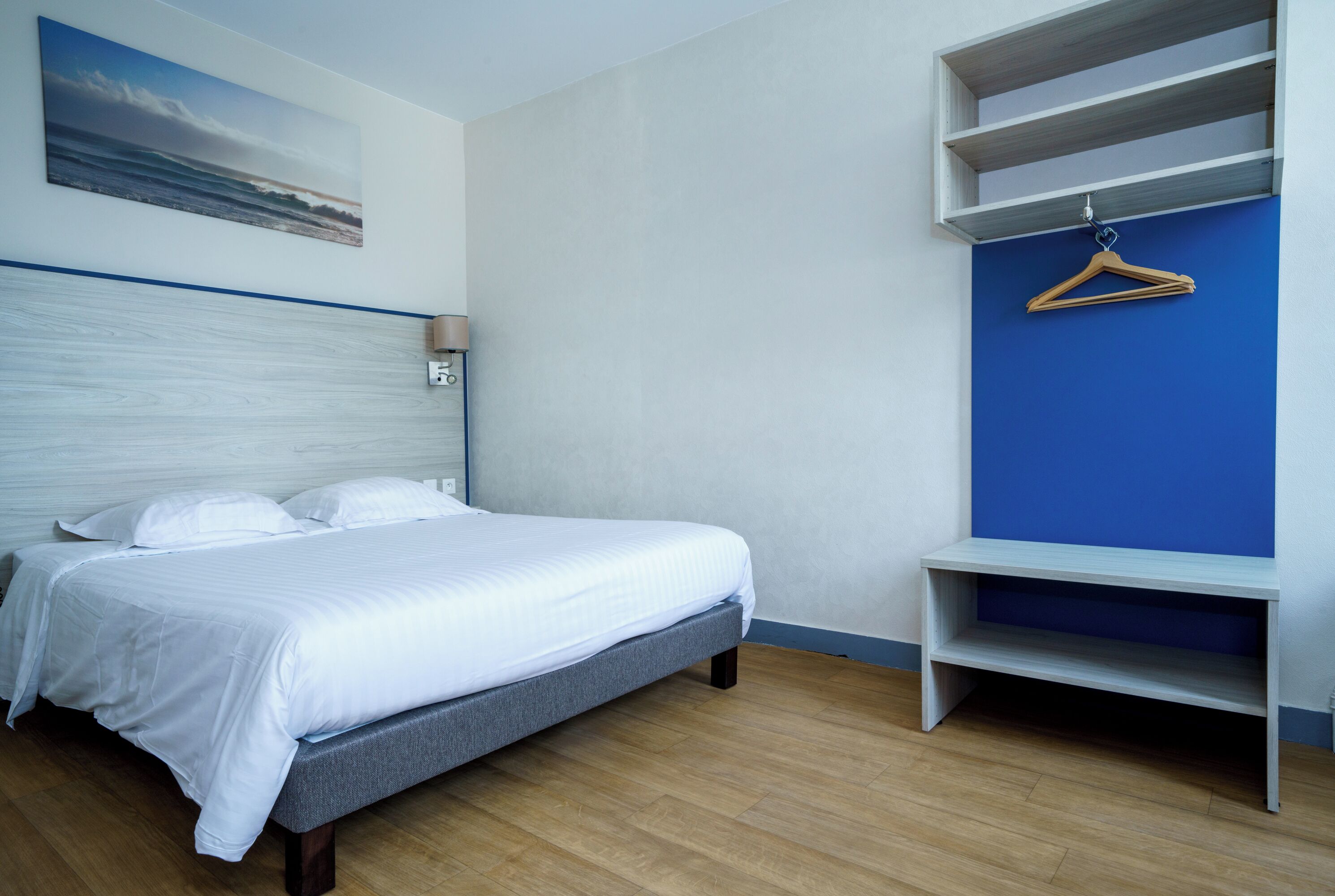 A bedroom with a bed, a wall-mounted shelf, and a painting.