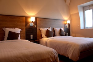 A hotel room with two beds, wooden headboards, bedside lamps, and a window.