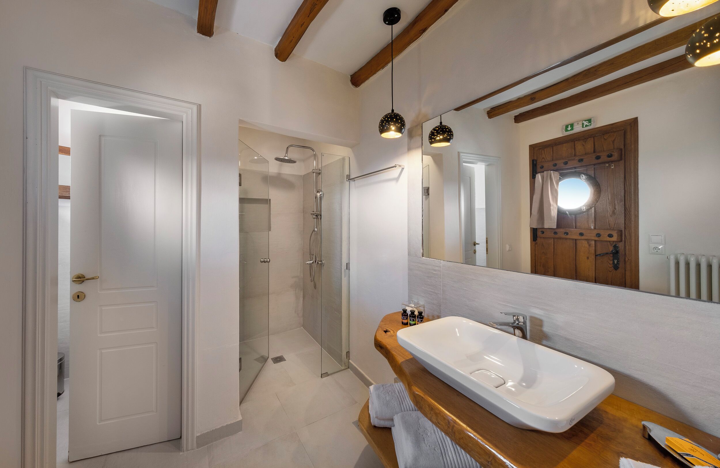 A modern bathroom with a large mirror, a wooden vanity, and a walk-in shower.