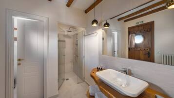 A modern bathroom with a large mirror, a wooden vanity, and a walk-in shower.