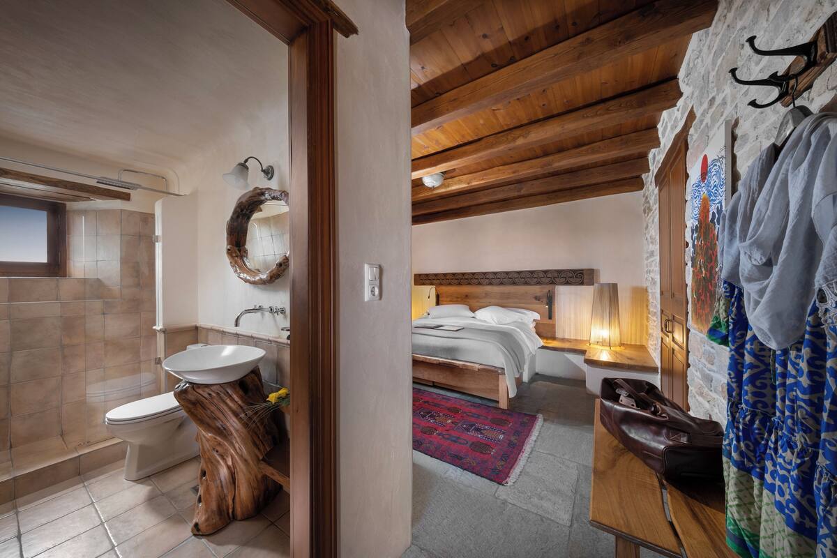 A modern bathroom with a wooden vanity, a large mirror, and a shower area.