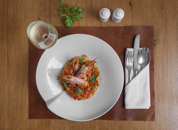 A plate of pasta with shrimp and basil on a wooden table. - Sakali Mansion (South Pelion)