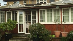 A residential house with a front door, windows, and steps leading to the entrance. There are potted plants and a small garden area. - Colnbrook Lodge Guest House (Slough)