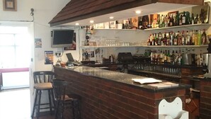 A bar area with a brick counter, stools, shelves with bottles, and a television. - Colnbrook Lodge Guest House (Slough)
