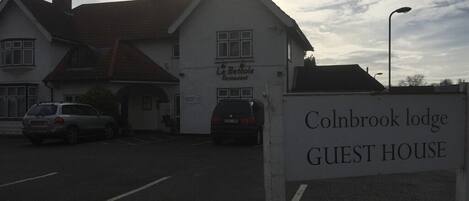 Un edificio con la targa "Colnbrook Lodge Guest House" e un cartello di fronte.