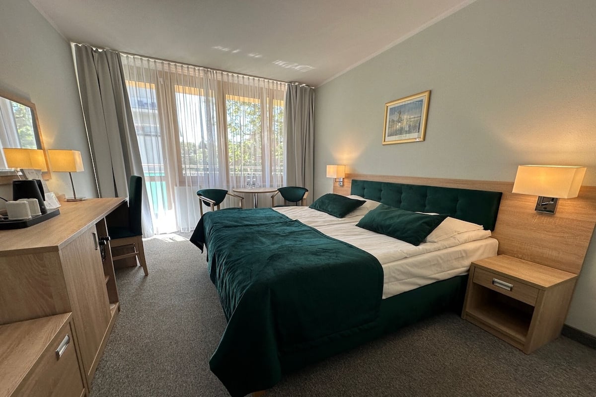 Ein Hotelzimmer mit Bett, Nachttischen, einem Schreibtisch und einem Sessel.