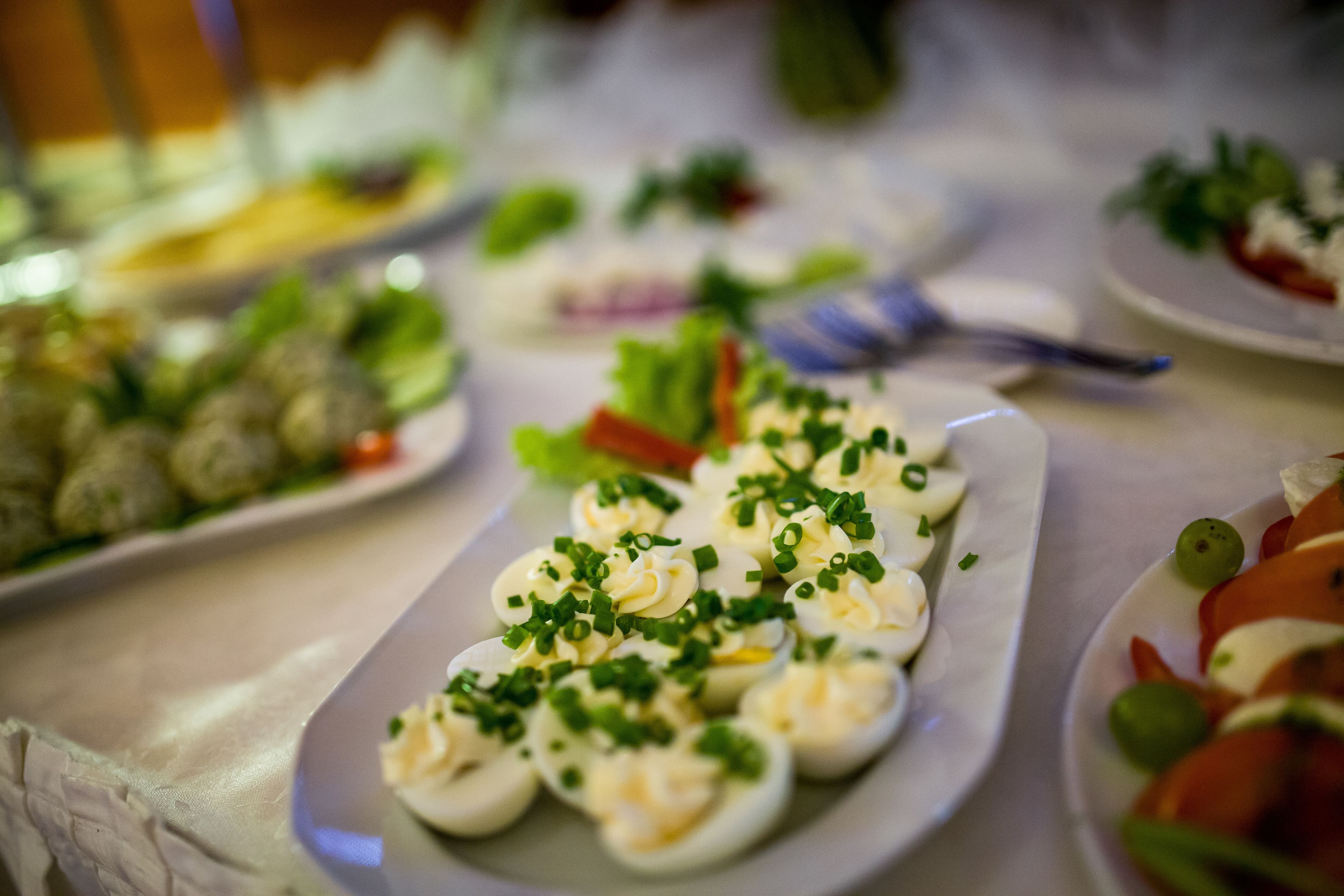 Een buffet met diverse gerechten, waaronder gevulde eieren, versierd met bieslook.