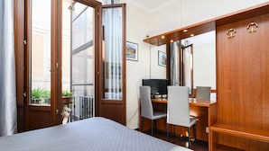 Una habitación de hotel con una cama, un escritorio con ordenador, una silla y un armario.