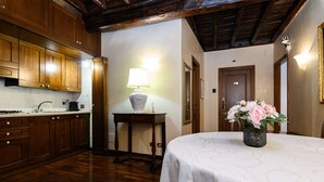 Una cocina con armarios de madera, una mesa con mantel blanco y un jarrón con flores.