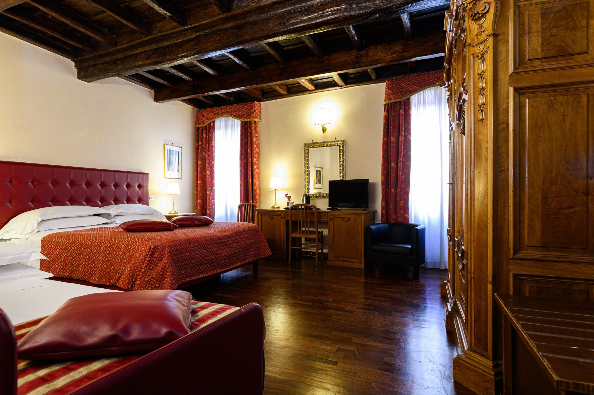 Habitación de hotel con una cama grande, un escritorio, una silla y un televisor.