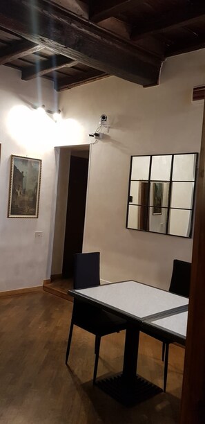 A room with a wooden ceiling, a table with chairs, a framed painting, and a mirror on the wall. - Domus Julia (Rome)