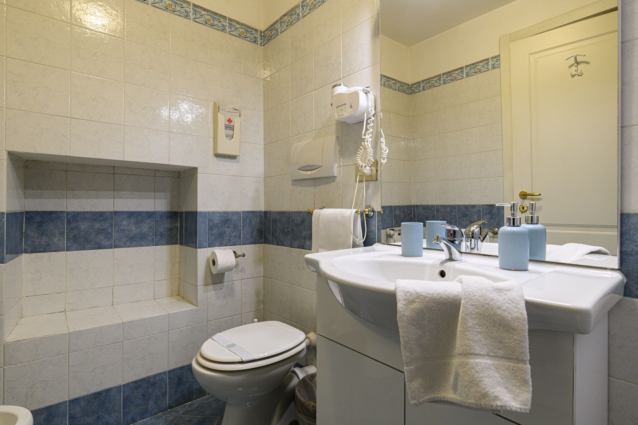 A bathroom with a toilet, sink, and hand dryer.