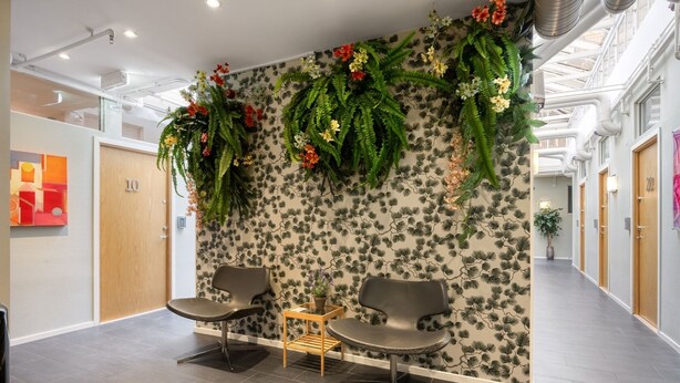 A modern waiting area with two chairs, a small table, and a floral wall design. - City Hostel (Stockholm)