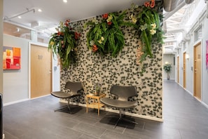 Un área de espera moderna con dos sillas, una mesita y un diseño floral en la pared.