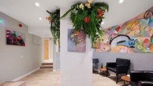A hotel lobby with a staircase, seating area, and a colorful mural. - City Hostel (Stockholm)