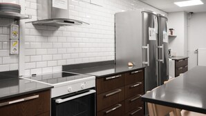 A modern kitchen with white tiled backsplash, stainless steel appliances, and wooden cabinetry. - City Hostel (Stockholm)