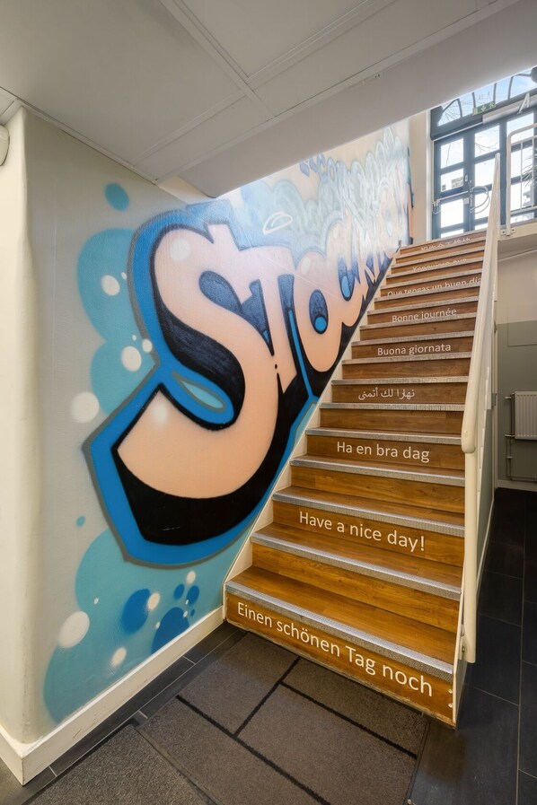 A staircase with a mural featuring the word 'Stockholm' and multilingual greetings. - City Hostel (Stockholm)