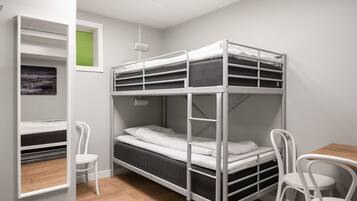 A bunk bed room with a desk and chairs, a window with blinds, and a picture on the wall.