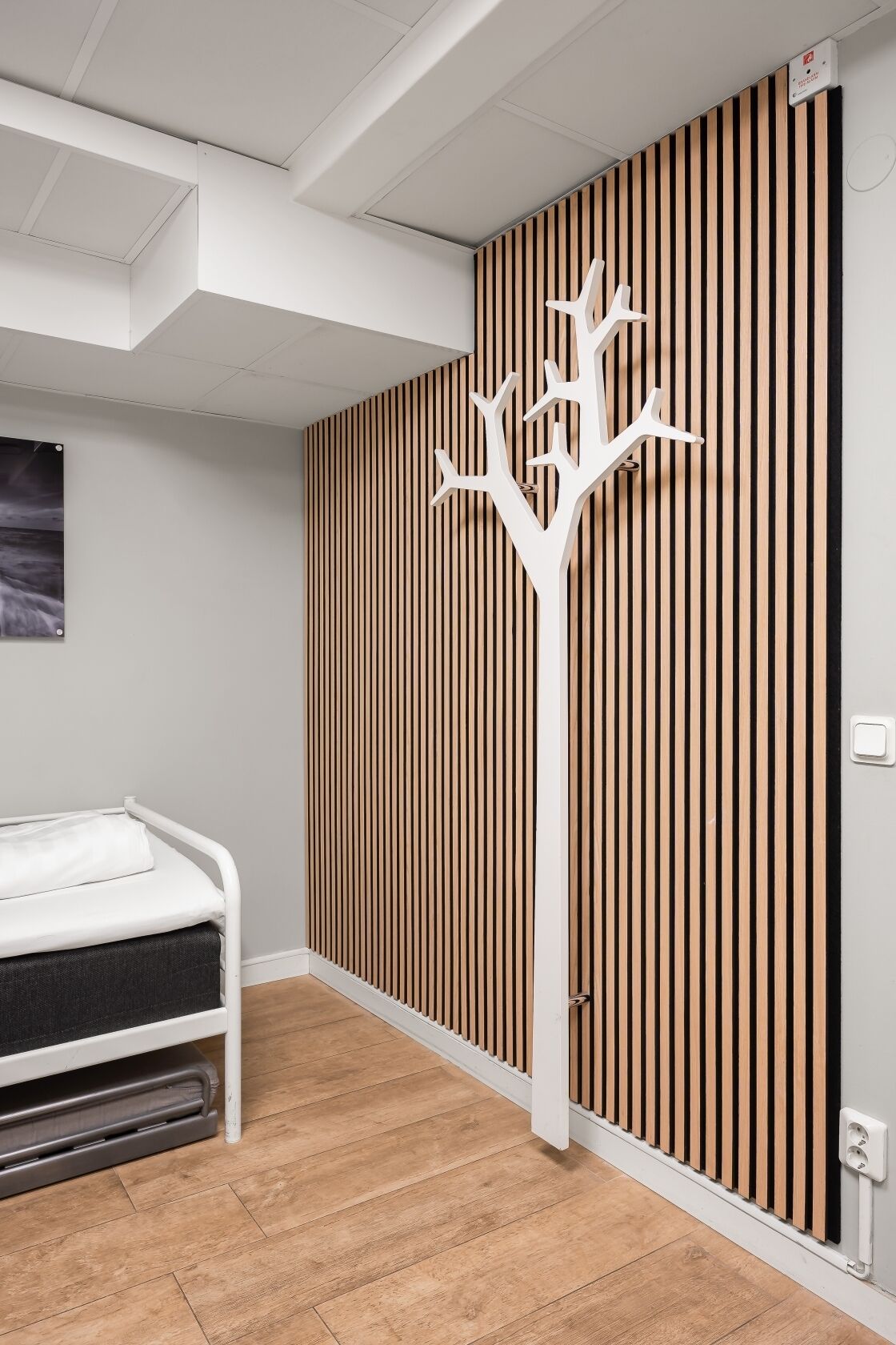 A bedroom with a bed, a white wall-mounted radiator, and a wooden slat partition.