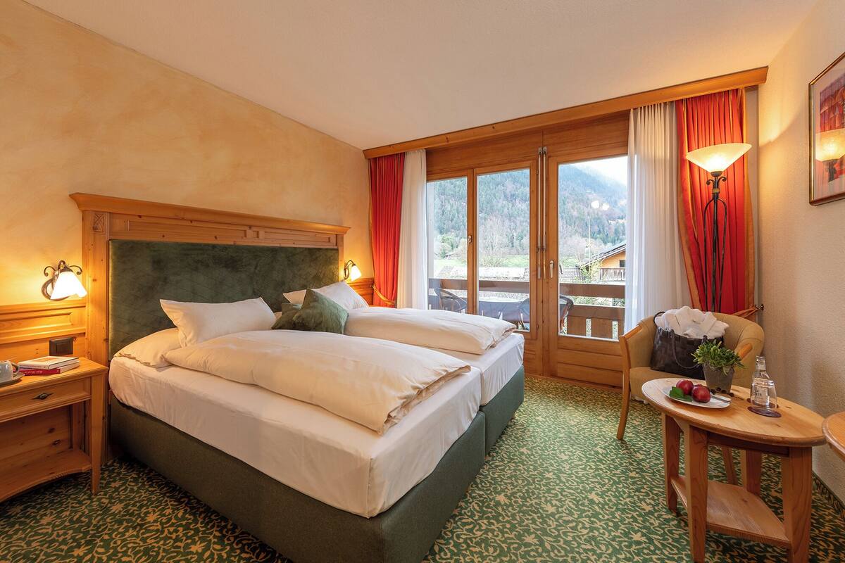 A hotel room with a large bed, wooden headboard, and a view of the outdoors through a sliding door.