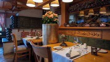 A restaurant interior with wooden furniture, a large vase with flowers, and a decorative wall with a fish tank.