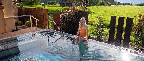 A person sitting by a pool with a mountain view in the background.