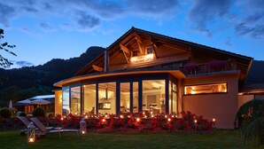 Une maison moderne avec une grande façade en verre, un balcon orné de fleurs et une enseigne indiquant « Centre de bien-être et de soins ».