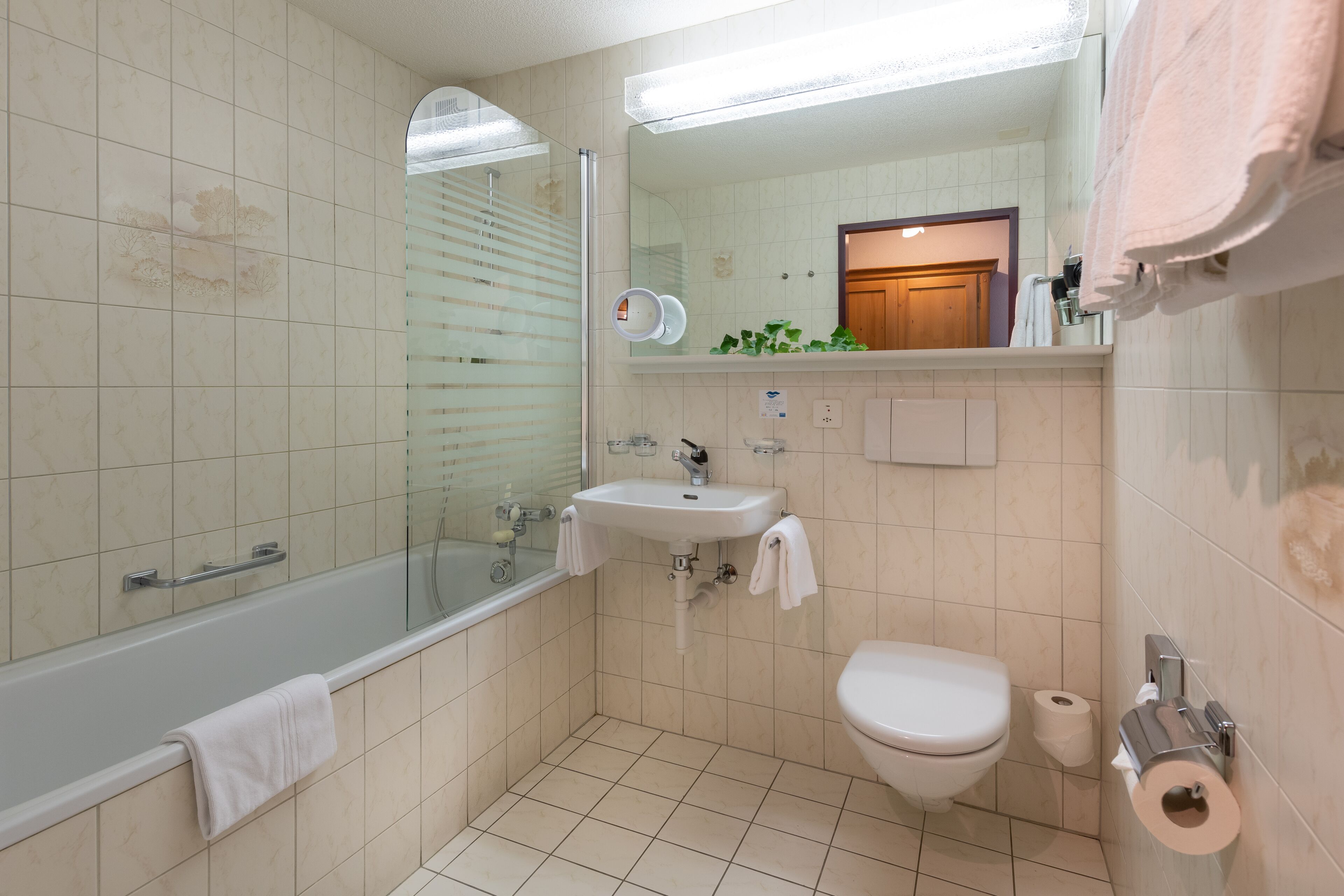 A bathroom with a bathtub, sink, toilet, and a mirror.