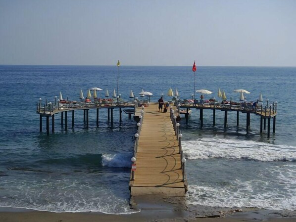 A pier with multiple umbrellas and lounge chairs extending into the water.