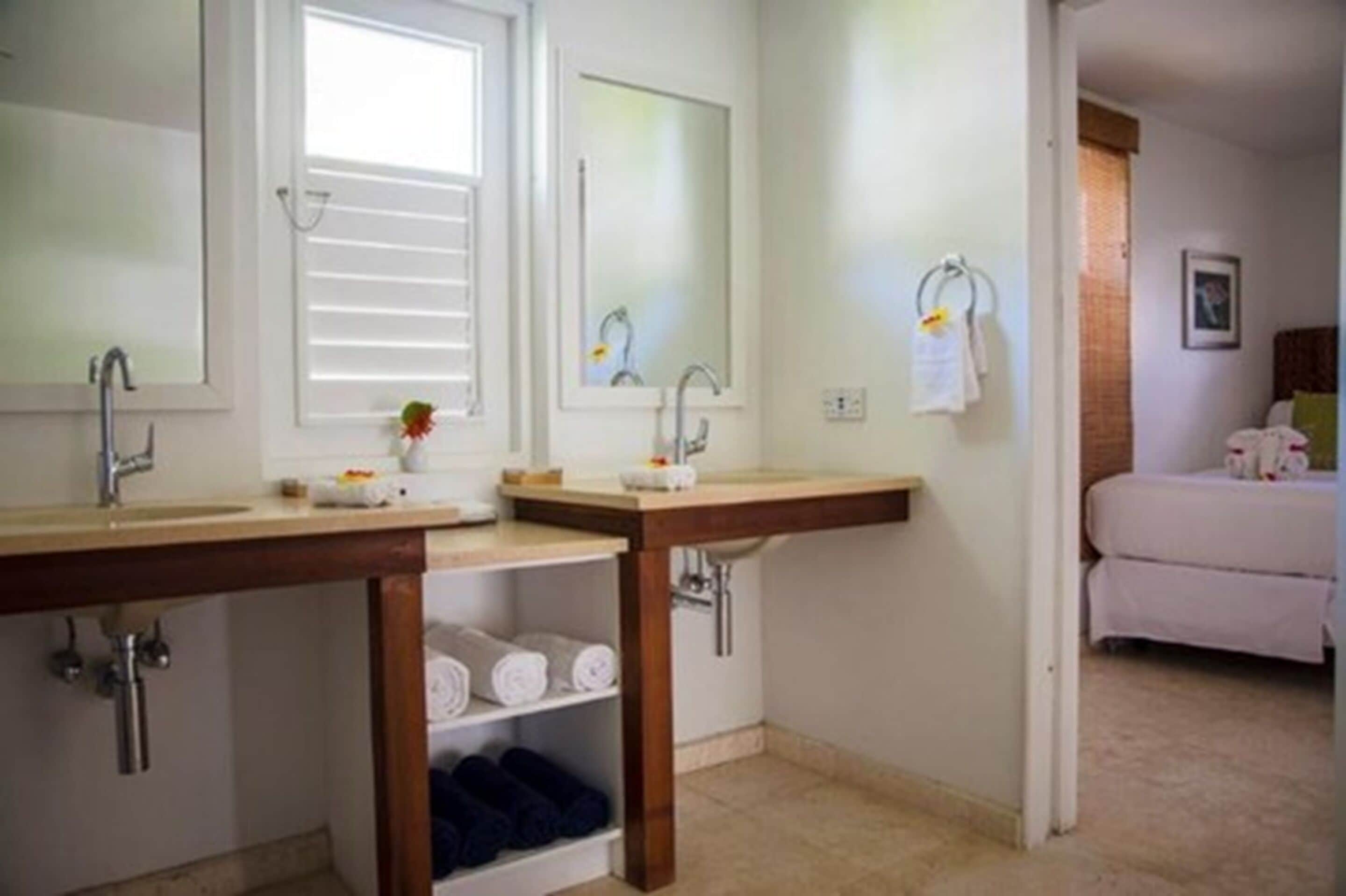 A bathroom with two sinks, a mirror, and a towel rack.