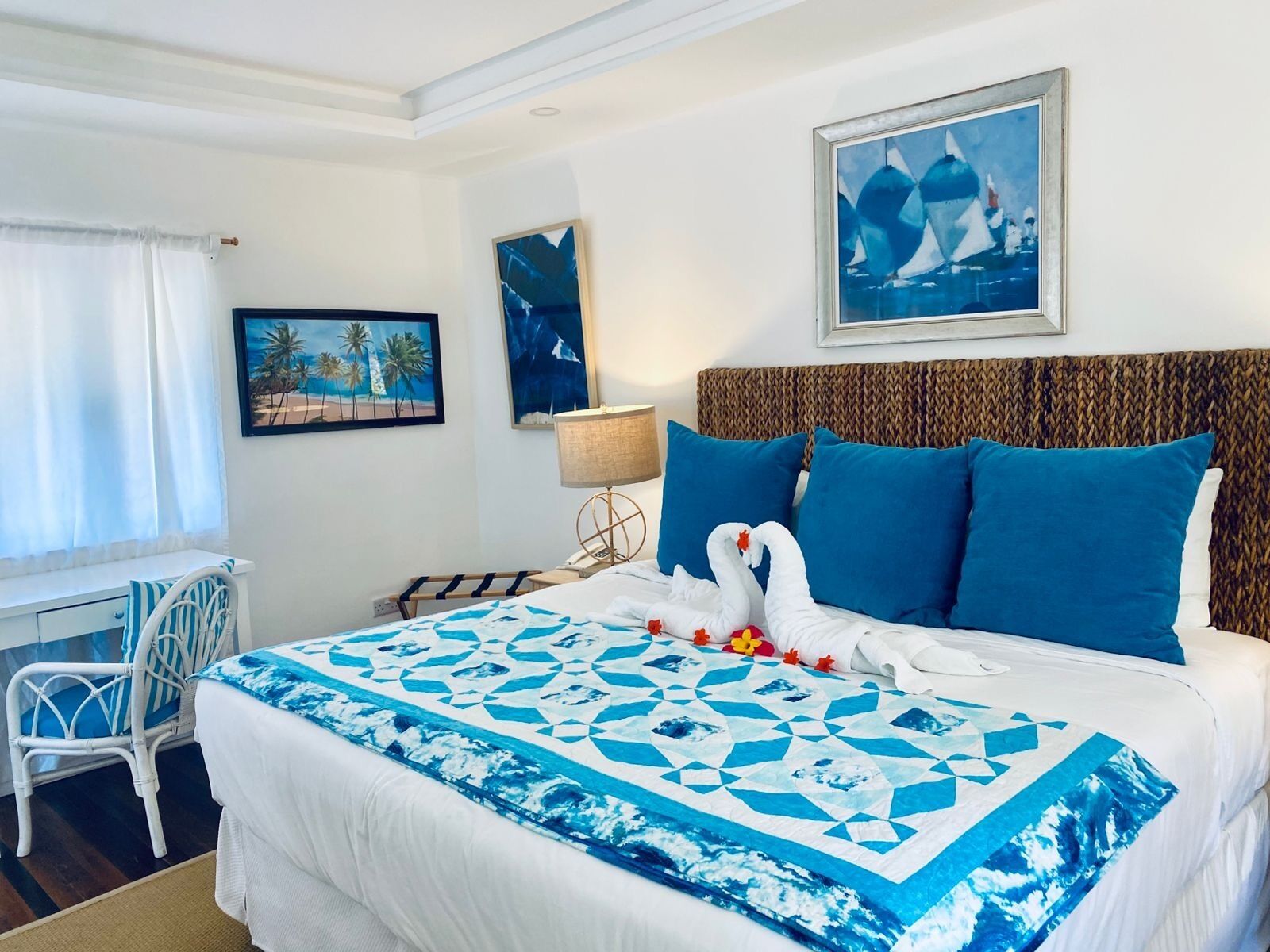 A hotel room with a bed, a desk, a chair, and artwork on the walls.